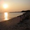 Spiaggia al tramonto con ringhiera di legno.