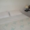 Letto matrimoniale con lampada e fiori su ripiano.