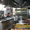 Cuoco prepara cibo in cucina industriale.