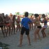 Gruppo di giovani che ballano sulla spiaggia sotto il sole.