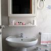Lavabo bianco sotto uno specchio con mensola.