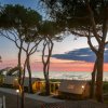 Bungalow tra alberi al tramonto sul mare.