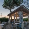 Terrazza all'aperto con tavoli e sedie sotto un tetto illuminato.