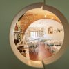 Sala da pranzo vista attraverso un pannello rotondo, con tavoli apparecchiati.