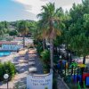 Piscina con palme e area giochi per bambini.