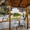 Veranda con tavolo e sedie, vista mare e alberi.