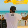 Persona in spiaggia sotto un ombrellone giallo.