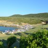 Spiaggia con lettini e ombrelloni vicino a colline verdi.