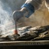 Chef che cucina pesce su una griglia fumante.