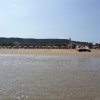 Spiaggia con ombrelloni e barca a vela.