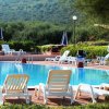Una piscina con lettini bianchi in un giardino.