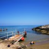Una passerella conduce al mare con persone che nuotano.