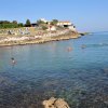 Persone nuotano in un mare calmo vicino a una costa rocciosa.