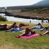 Persone che fanno yoga sull'erba vicino al mare.