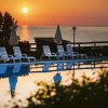 Piscina con lettini e ombrelloni al tramonto.