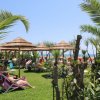 Lettini su prato con ombrelloni di paglia vicino al mare.