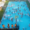 Persone che nuotano e si divertono in una grande piscina all'aperto.