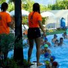 Due istruttori in magliette arancioni osservano i nuotatori in piscina.