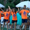 Un gruppo di persone in magliette arancioni esegue una danza all'aperto.