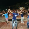 Spettacolo serale all'aperto con persone che ballano sul palco davanti a un pubblico.