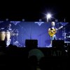Band che si esibisce su un palco con chitarra, percussioni e batteria.