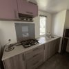 Cucina con piano cottura, lavello, pensili e frigorifero, finestra luminosa.
