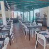 Sala da pranzo con tavoli e sedie bianche, soffitto e travi turchesi.