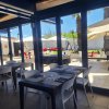 Ristorante con tavoli apparecchiati, vista su terrazza esterna con ombrelloni.