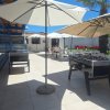 Tavoli da calcio balilla sotto ombrelloni in una terrazza soleggiata con sedie e tavoli all'aperto.