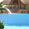 Una cascata in piscina sotto una tettoia di paglia.