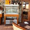 Interno di un ristorante accogliente con tavoli apparecchiati e mobili in vimini.