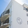 Edificio bianco con balconi curvi e sole.
