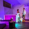 Spa illuminata con due persone e vasca idromassaggio.