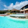 Piscina con cascata e ombrellone beige.