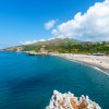 Spiaggia con vista su mare blu e colline.