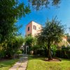 Viale con prato e alberi conduce a una villa rosa.