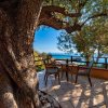 Terrazza con tavolo vista mare e alberi.