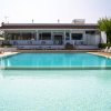 Piscina con sdraio e un edificio sullo sfondo.