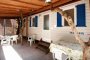 Veranda con tetto in legno, sedie e tavolo.