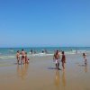 Spiaggia affollata con bagnanti in mare.
