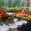 Buffet di frutta fresca su tavolo con piatti.