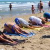 Persone fanno yoga su una spiaggia.