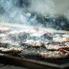 Carne grigliata su barbecue con fumo.