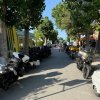 Strada alberata con moto parcheggiate.