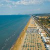 Lunga spiaggia con ombrelloni e mare.