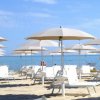 Spiaggia con ombrelloni bianchi e sedie a sdraio.