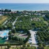 Vista aerea di un complesso turistico con piscina vicino al mare.